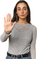 Hispanic young woman standing with outstretched hand showing stop sign, preventing you.