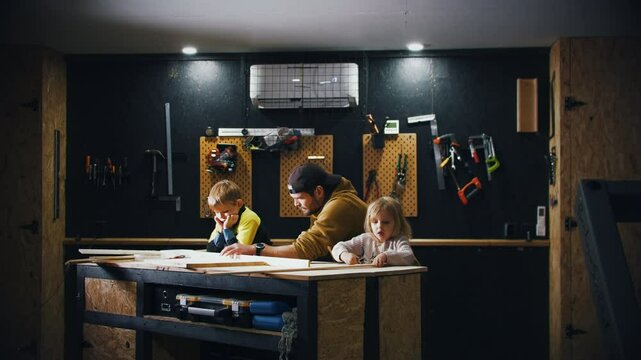 Young kids and dad working on creative woodworking project together in garage