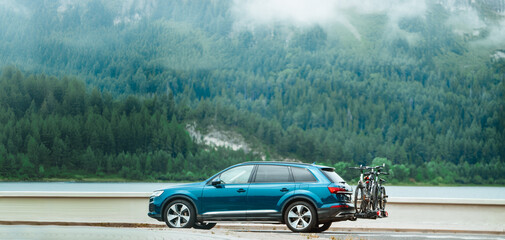 Fototapeta premium SUV with bikes on back driving past lake