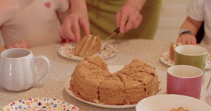 Family with children. Hand with delicious cake at a joyful gathering, family members are happily enjoying each others company around a table, kids eating cack.
