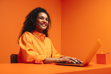 Smiling telemarketer woman with headphones in a vibrant monochromatic office space