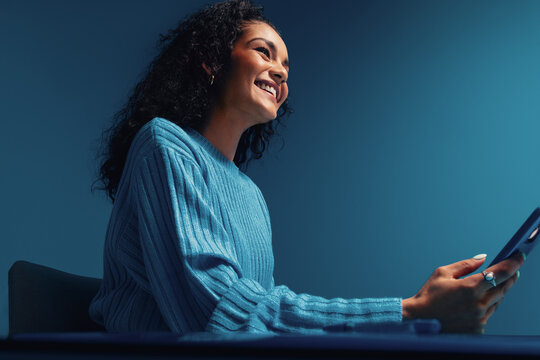 Blue monochromatic shot of young woman texting on smartphone