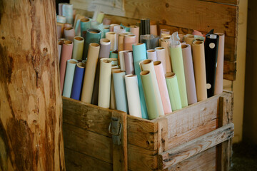 High angle shot old wooden box full of pastel colored gift wrapping paper rolls