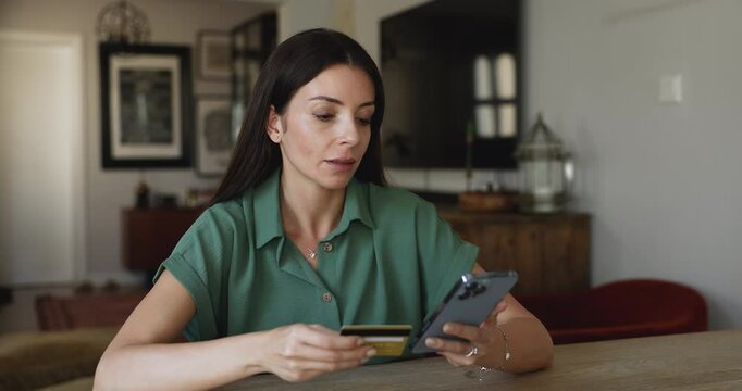 Woman smiling holding credit card and smartphone, doing online transactions, paying for electronic services, renewing favorite e-services or subscriptions, buying gifts or booking through mobile app