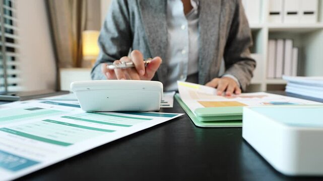 Young Asian accountant doing paperwork using laptop computer sitting in business office Make a financial report, analyze financial graphs or write tax forms.