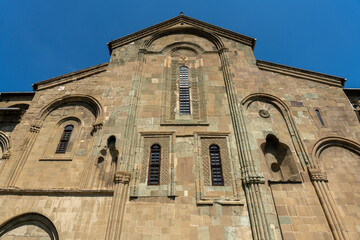 The building is old and has a lot of windows. The windows are small and there are arches on the sides. The building is very tall and has a lot of detail
