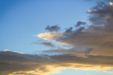 Sunset in the clouds. Fluffy clouds in the blue sky at sunset. A bunch of clouds. Beautiful sky at sunset. 