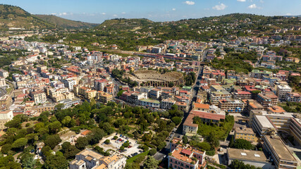 Fototapeta premium Aerial view of the Flavian Amphitheater, located in the historic center of Pozzuoli, near Naples, Italy. In the background is the train station. 