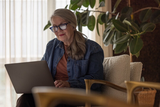 Senior woman using a laptop at home in her living room
