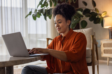 African american woman sitting on floor using a laptop at home