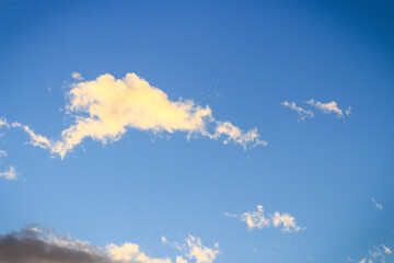 Sunset in the clouds. Fluffy clouds in the blue sky at sunset. A bunch of clouds. Beautiful sky at sunset.