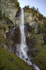 Majestic waterfall cascading down rocky cliffs along the Grossglockner Hochalpenstrasse in Austria during a tranquil afternoon