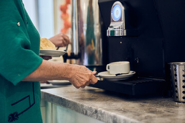 A woman prepares fresh, fragrant coffee using a modern coffee maker. With space to copy. High quality photo