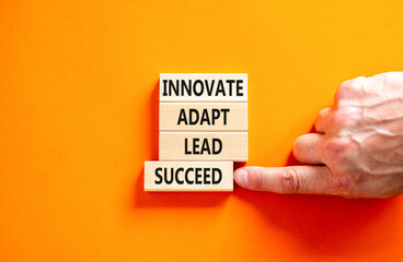 Innovate adapt lead succeed symbol. Concept words Innovate Adapt Lead Succeed on beautiful wooden blocks. Beautiful orange background. Business innovate adapt lead succeed concept. Copy space.