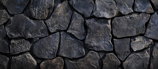 Rugged black stone surface texture with uneven edges ideal for background or overlay with space for text or design elements.