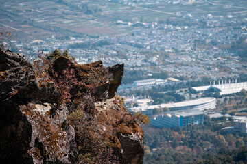 A dramatic cliff edge in Dali, Yunnan, China overlooks a sprawling city and stadium below.  The...