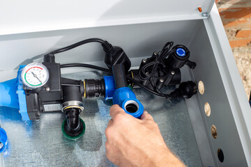 A man installs a drip irrigation system by placing a polypropylene compression tee into a metal box