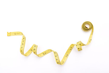 Yellow measuring tape curving on white background with copy space