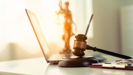 Online law and justice concept on table in modern office Next to the wooden hammer and scales of...