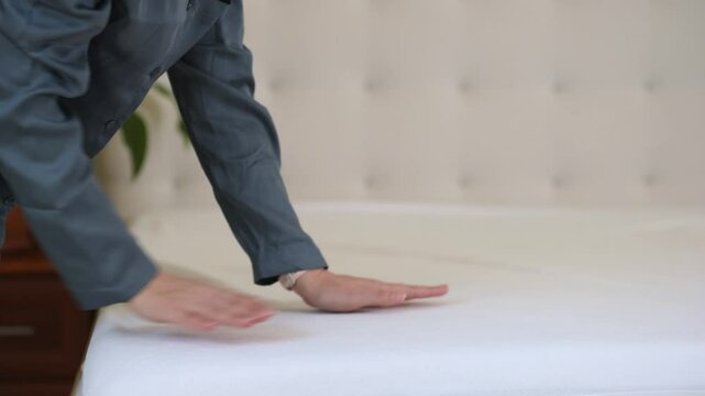 A woman in the pajama makes her bed