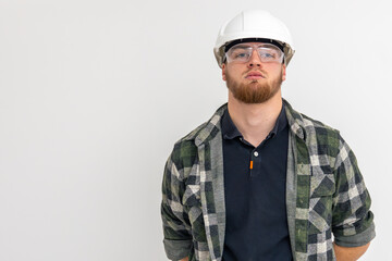 Portrait of a male builder. Engineer in overalls and helmet on a light background.