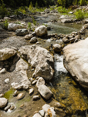 Long exposure shot of the calm river with a rocky shore in the forest at sunset.