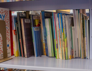 Children's books neatly organized on a white bookshelf in a library or classroom setting. Cleveland, Ohio, USA