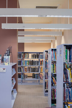 Interior view of a library with bookshelves lined with books and bright fluorescent lighting. Cleveland Library, Ohio, USA