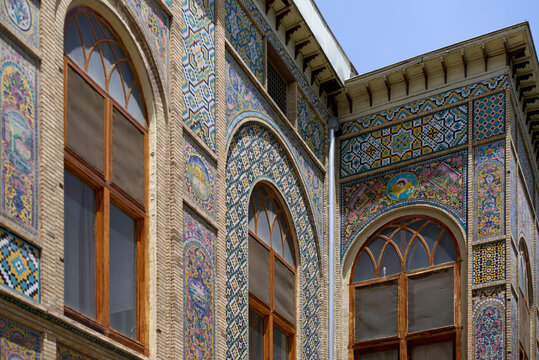 Intricate mosaic tilework adorns the facade of a historic building with arched windows, Teheran, Iran