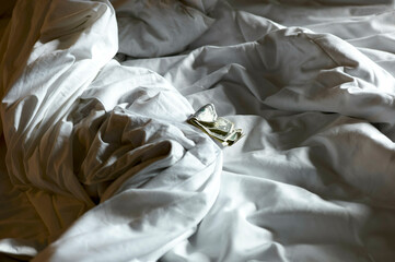 A crumpled US dollar note on a messy white bedsheet in soft lighting, New Orleans, USA