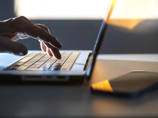 Man working online on his laptop computer with sunlight coming through window
