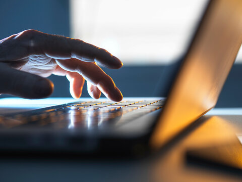Man working online on his laptop computer with sunlight coming through window