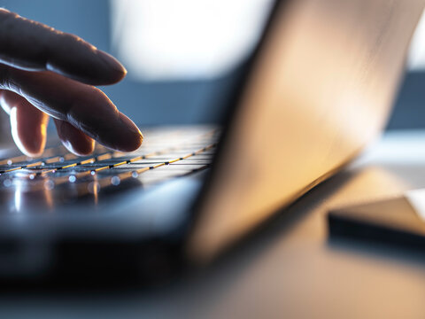 Man working online on his laptop computer with sunlight coming through window
