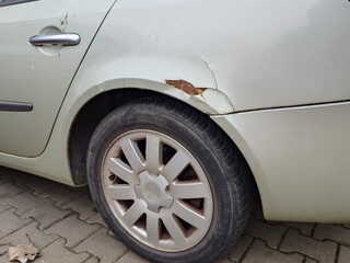 Dented and rusting car wheel arch. Close up shot, no people