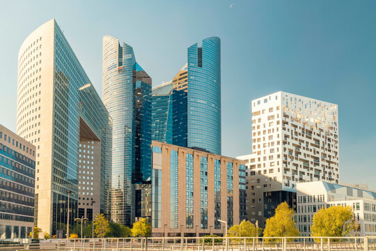 Modern skyscrapers at La Defense with reflective glass facades towering above a cityscape under a clear blue sky, Paris, France