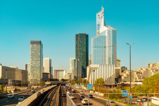 Urban skyline with modern skyscrapers at La Defense and a busy highway under clear blue skies, Paris, France