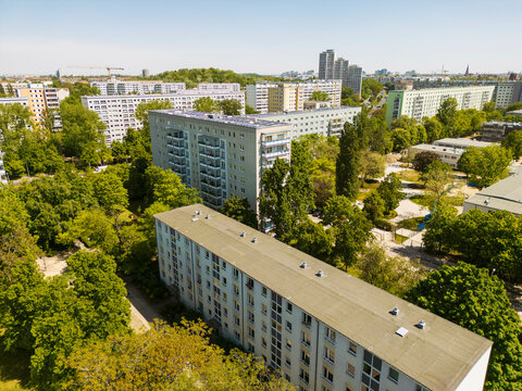 Aerial view of a residential area with apartment buildings surrounded by lush green trees under a clear sky, Berlin, Germany
