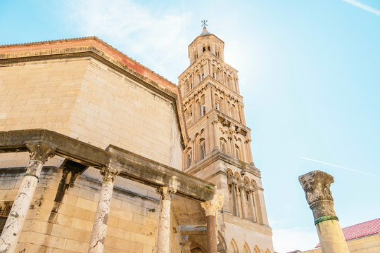Ancient stone building with a bell tower of St Domnius Cathedral and classical columns under a clear blue sky, Split, Croatia