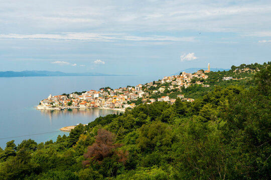 Coastal town of Igrane nestled on a hill overlooking a serene sea under a partly cloudy sky, Croatia