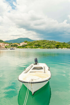 Boat anchored to a dock with lush green backgrop and mountains in the back ground and turquoise blue water of the Adriatic sea, Mali Ston, Croatia