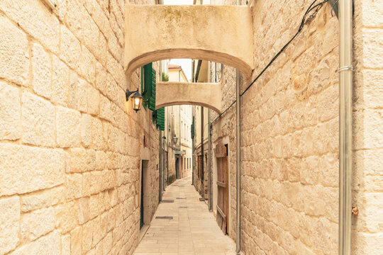 Narrow cobblestone alleyway with stone walls and arch in the historical city of Omis, Croatia