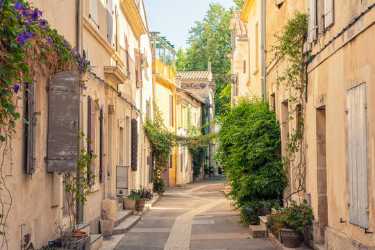 Narrow street with colorful shutters and historic buildings in Arles, France - Powered by Adobe