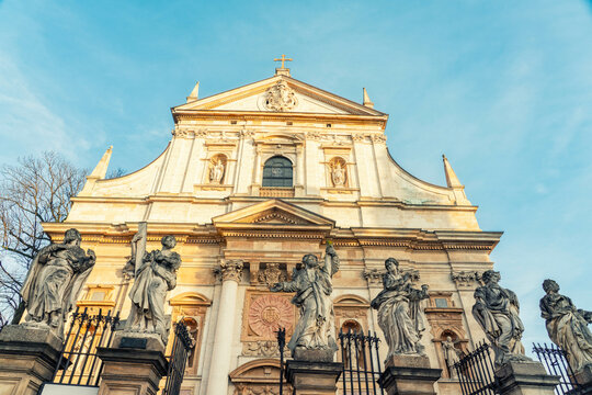 Historic Saints Peter and Paul Church facade with sculptures under a clear blue sky during sunset, Krakow, Poland