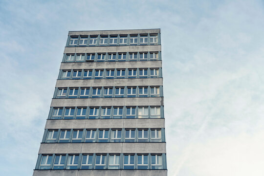 Modern concrete building with repetitive windows against a cloudy sky, Krakow, Poland