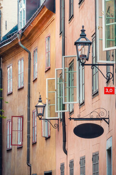 Orange and pink facades of old buildings with vintage street lamps and signage in an atmospheric alley in Gamla Stan, Stockholm, Sweden