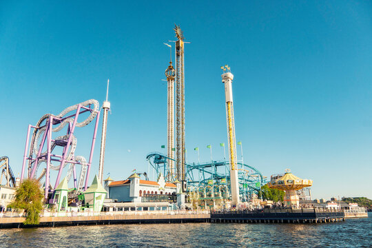Amusement park Gr&ouml;na Lund with roller coasters and thrill rides by the water under a clear blue sky, Stockholm, Sweden.