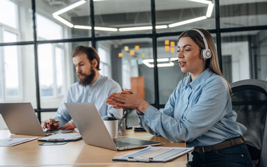 Working by laptops. Man and woman are in the office together
