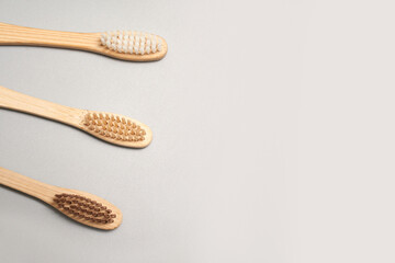 Three eco friendly bamboo toothbrushes with natural bristles on light gray background.