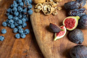 Autumn fruits and nuts (grapes, figs, prunes, walnuts) on wooden platter on wooden chest