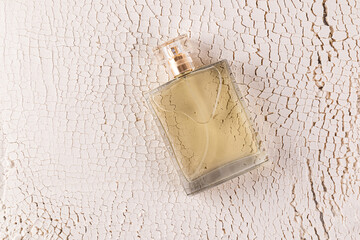 Transparent male perfume bottle on sandy white background